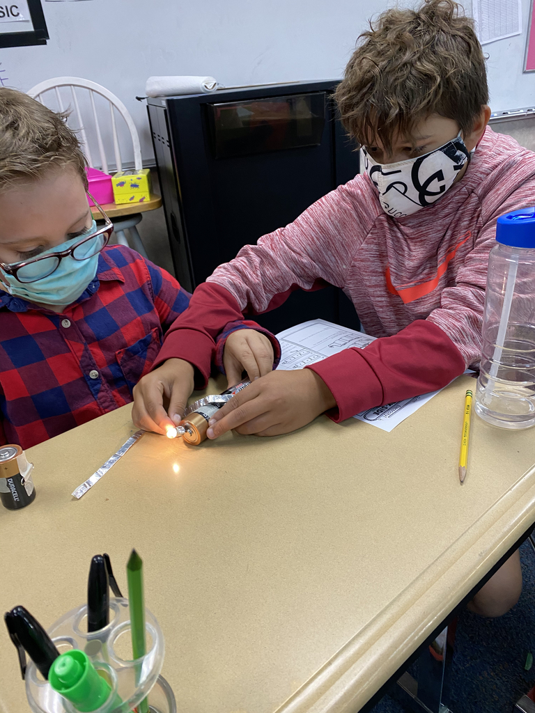 4th grade students using foil strips and batteries to illuminate a miniature light bulb. 